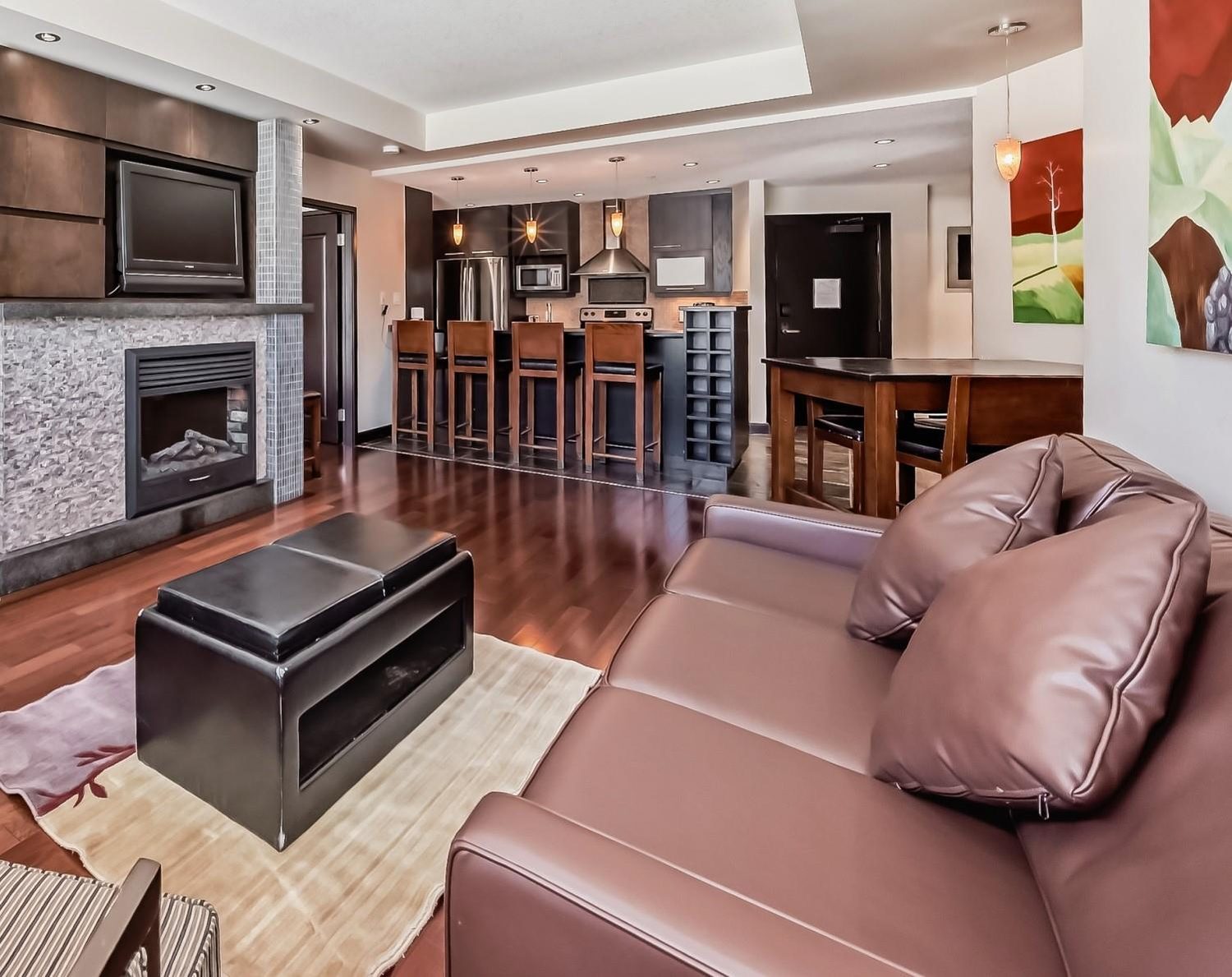 A suite's living room, with a leather sofa, a fireplace and a kitchen counter