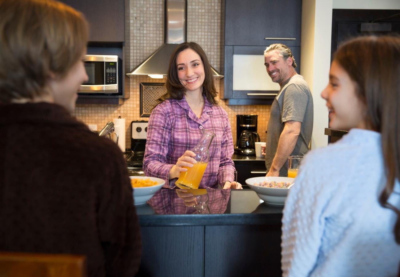 Adults and children talking together in the kitchen of a suite