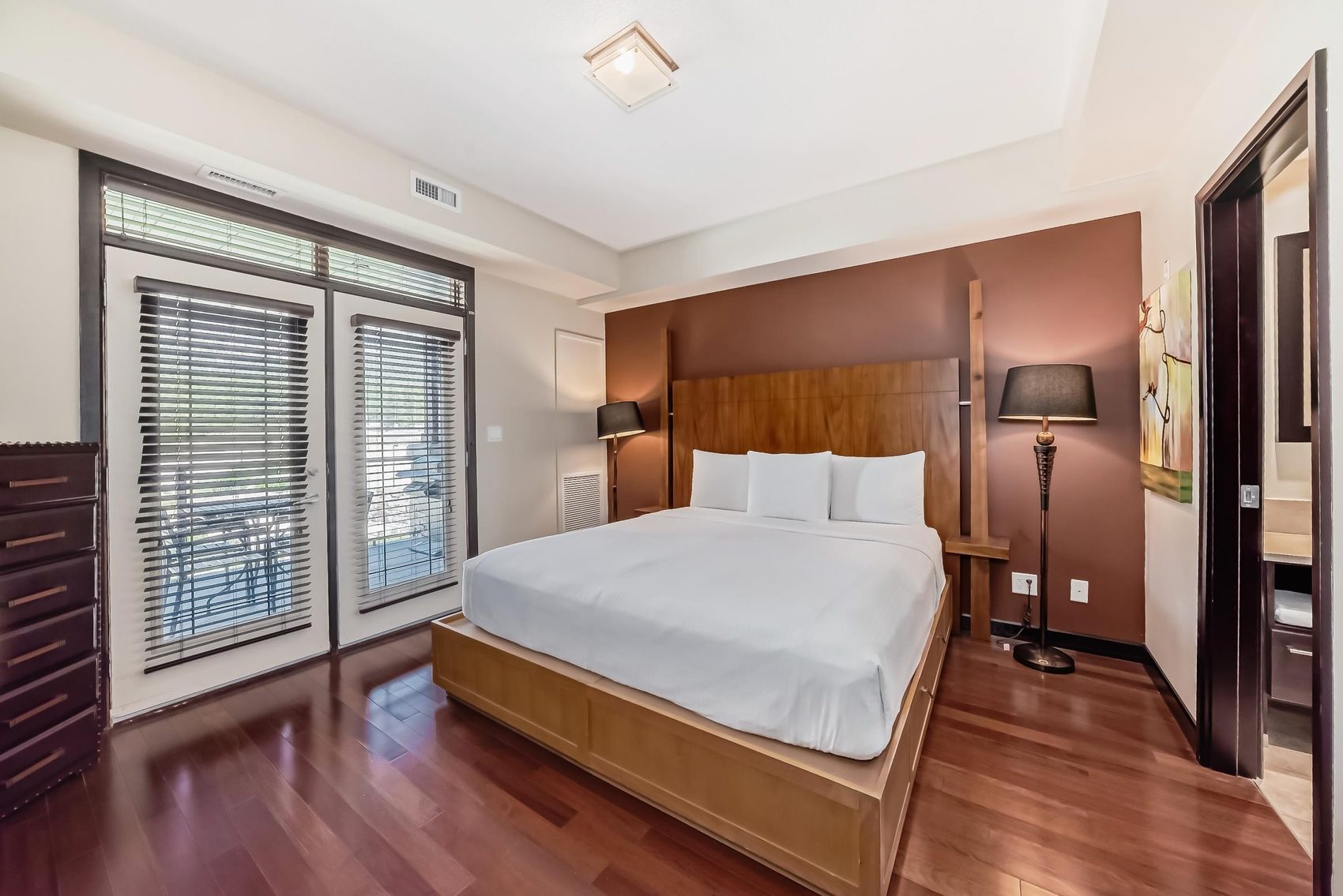 A suite bedroom with a king bed and doors to a patio