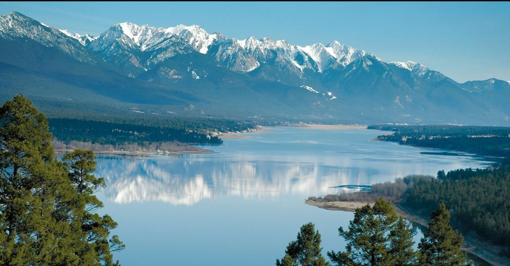 The Columbia Valley seen from above: a wide, calm lake with snow-topped mountains beyond