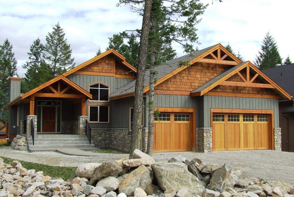 A craftsman-style bungalow with timber-trimmed gables, a stone base and wood garage doors
