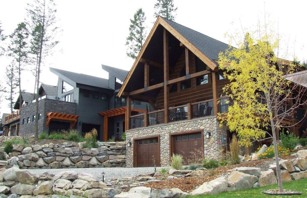 Timber-frame homes with stone bases among boulders and young trees