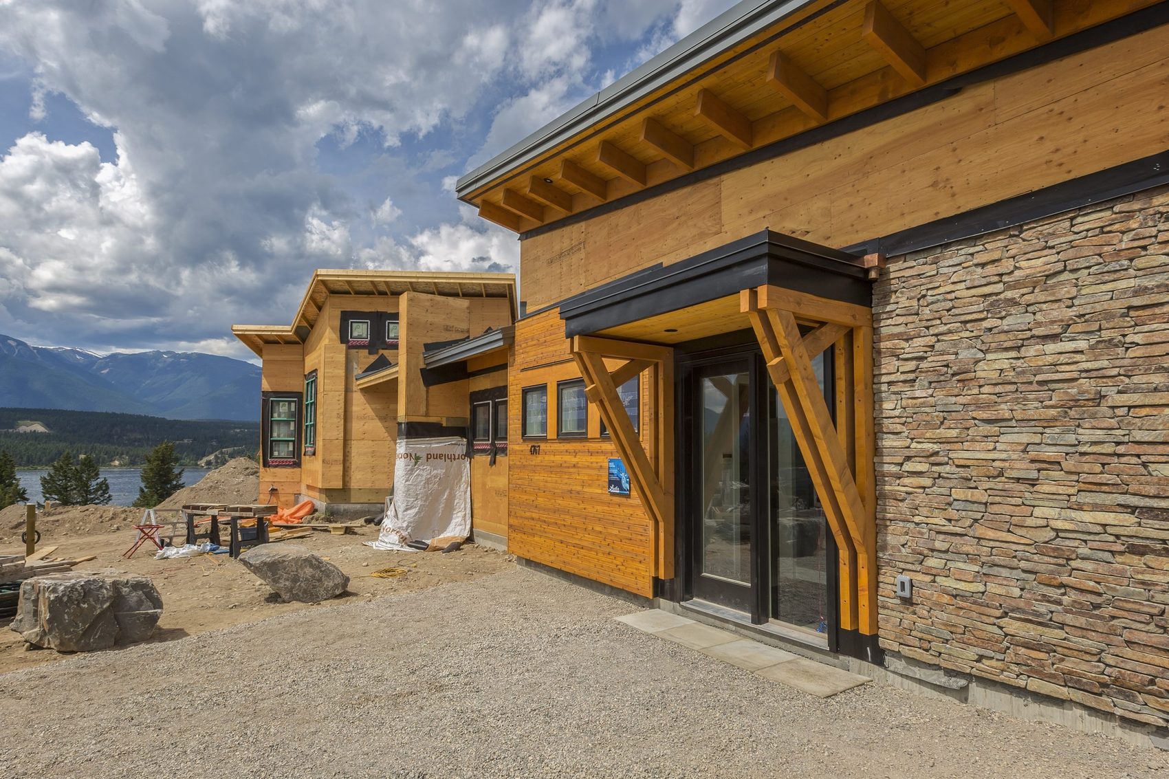 The timber, glass and stone entrance of a modern home, with mountains beyond