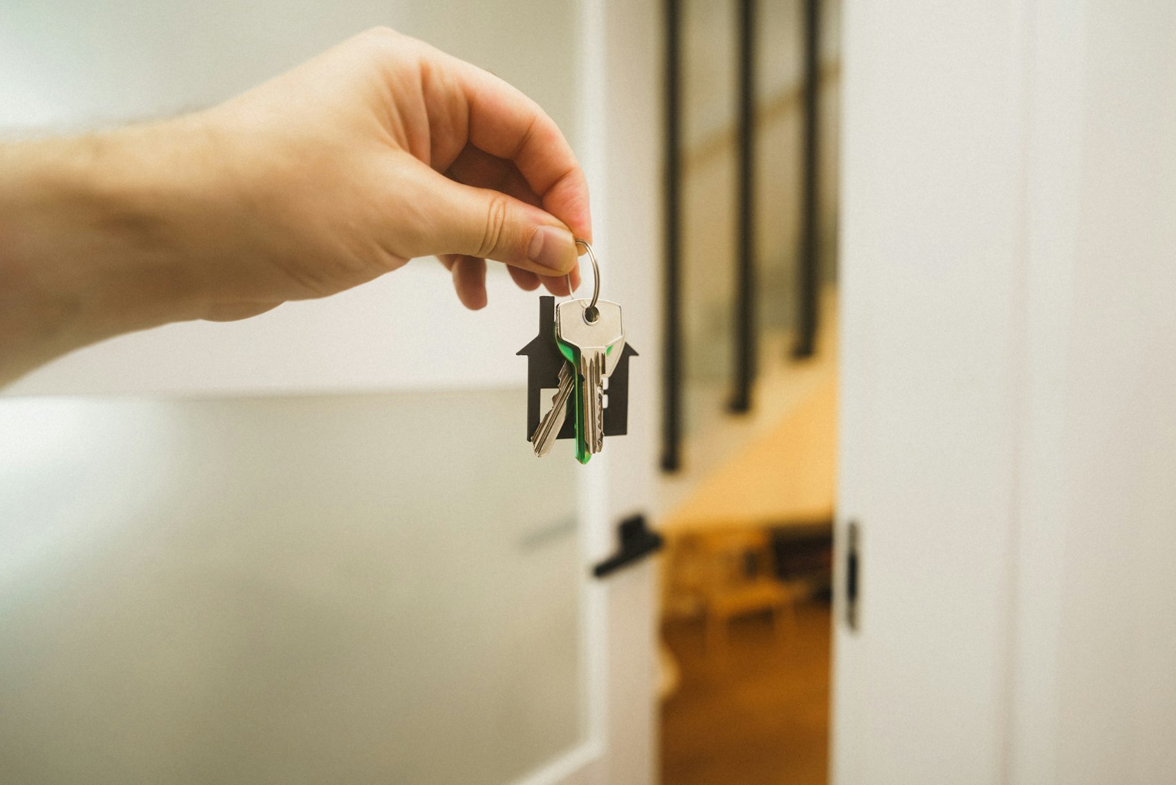 A hand holding a set of house keys on a house-shaped key ring