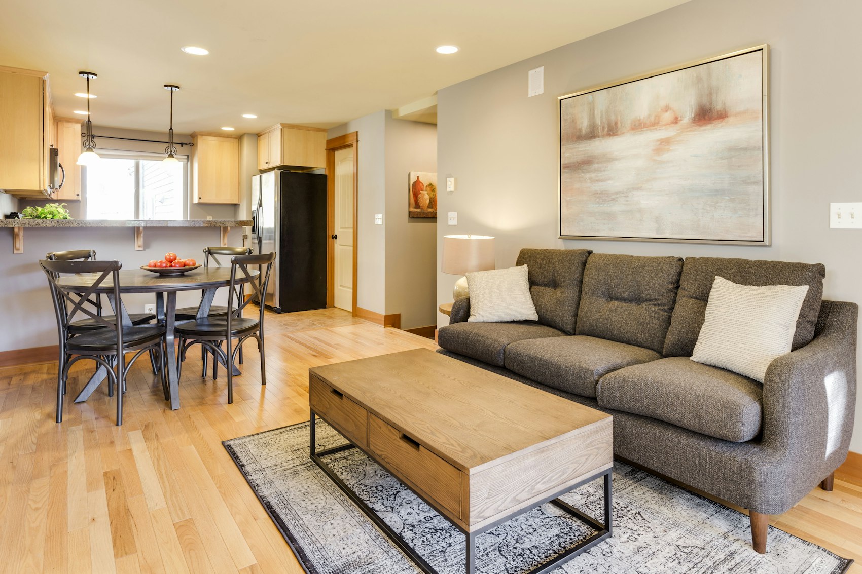 An open living room with a sofa and coffee table, and a kitchen and dining table beyond